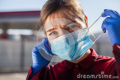 Worried young woman putting PPE face mask on/taking it off in public Stock Photo