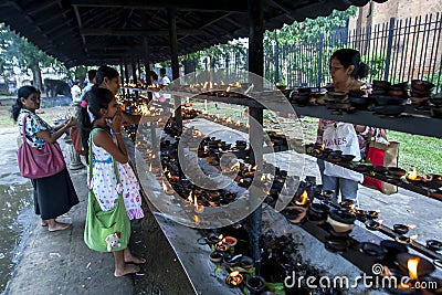 Worshippers light oil lamps within the Temple of the Sacred Tooth Relic in Kandy, Sri Lanka. Editorial Stock Photo