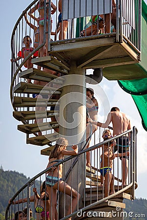 WORTHERSEE, AUSTRIA - AUGUST 07, 2018: People climbing the ladder to the water park slide start Editorial Stock Photo