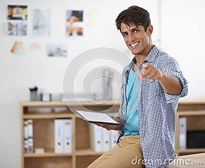 Would you like to know the secret to success. A handsome young ethnic businessman holding a tablet while pointing at the Stock Photo