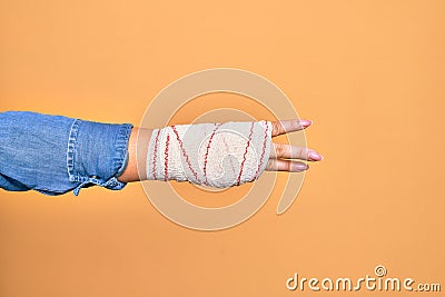 Wounded hand of caucasian young woman cover with bandage doing number three with fingers over isolated yellow background Stock Photo