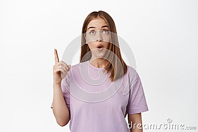 Wow so awesome. Young woman pointing and looking up with fascinated, impressed face, found smth in store worth attention Stock Photo