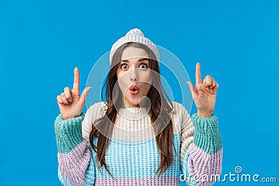 Wow so cool, check this out. Impressed and astonished brunette woman in winter hat, sweater, folding lips amused Stock Photo