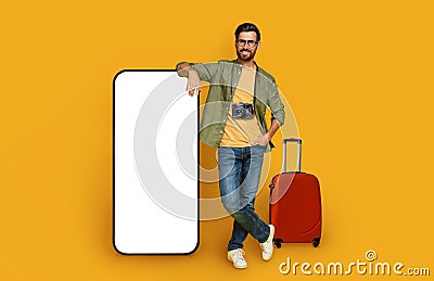 Cheerful man traveler posing by big smartphone, mockup Stock Photo