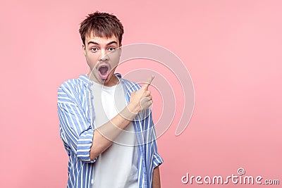 Wow shocking news! Portrait of amazed brown-haired man pointing at copy space for information, looking astonished. isolated on Stock Photo