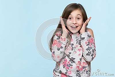 tudio portrait of an adorable young schoolgirl screaming with excitement, isolated on pastel blue backgroud. Stock Photo