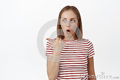 Wow thats amazing. Impressed teen girl pointing left, looking with astonished shocked face, checking out promo deal Stock Photo