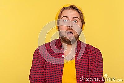 Wow, unbelievable! Shocked hipster guy in beanie hat and checkered shirt looking at camera with big eyes Stock Photo