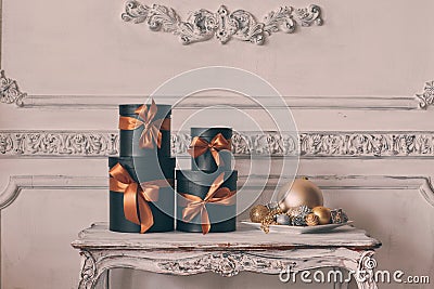 Wrapped gift black boxes with ribbons as Christmas presents on a table luxury white wall design bas-relief stucco Stock Photo