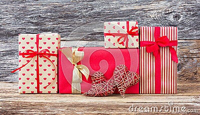 Wrapped gifts and two red hearts on wooden background. Toned, soft focus, vintage style Stock Photo