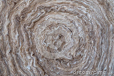 Wrapped in a roll in the clockwise direction fluffy wavy mineral wool consisting of hair layers of brown and white color. Stock Photo