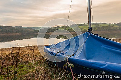 A wrapped up Yacht waits to be taken out on the reservoir in the Peak District during a relaxing sunset Stock Photo
