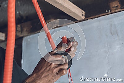 Wrapping the end of a live wire with electrical tape. Doing ceiling repair and renovation Stock Photo