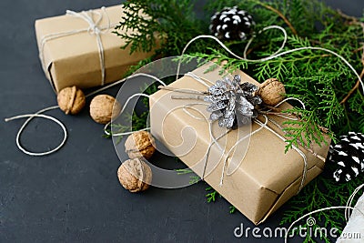 Wrapping rustic eco Christmas gifts with craft paper, string and natural fir branches on dark background Stock Photo