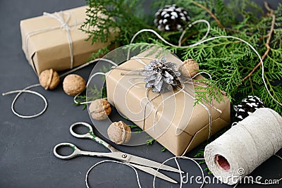Wrapping rustic eco Christmas gifts with craft paper, string and natural fir branches on dark background Stock Photo