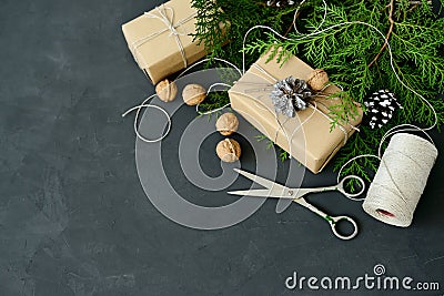 Wrapping rustic eco Christmas packages with brown paper, string and natural fir branches on dark background Stock Photo