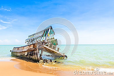 The wreckage of the fishing boat is beached with blue sea and the blue sky as background.location Satheep Thailand Stock Photo