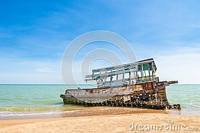 The wreckage of the fishing boat is beached with blue sea and the blue sky as background.location Satheep Thailand Stock Photo