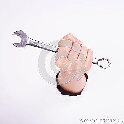 A wrench in the hand of a girl. Symbol of hard work, feminism and labor day. Isolate on white background Stock Photo