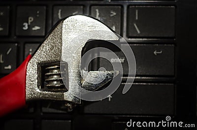 Wrench tool over a laptop on a dark background close up selective focus Stock Photo