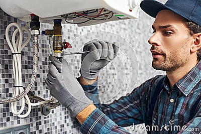 Wrench always with you. Worker set up electric heating boiler at home bathroom Stock Photo