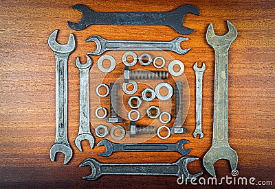 Wrenches, bolts, nuts and washers squared on a brown wood texture background Stock Photo