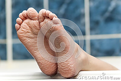 Wrinkled bare feet coming out from a bathtub. Young person getting a bath feet close-up indoor in bathroom interrior photo Stock Photo