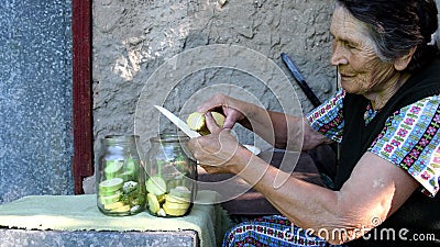 Elderly woman slice squash and put into jar Stock Photo