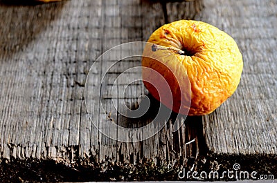 Wrinkled yellow apple on a board Stock Photo