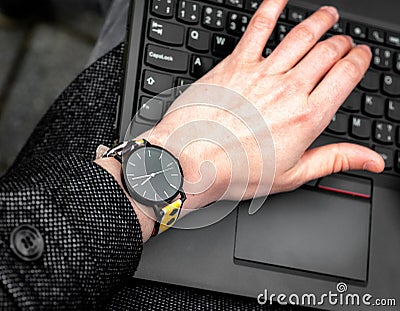 Wristwatch. Hand on the keypad of notebook Stock Photo