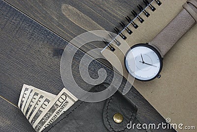 Wristwatch and notebook with money in wallet on wooden table Stock Photo