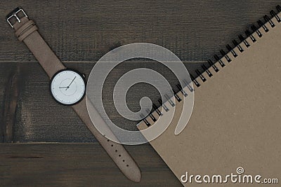 Wristwatch and notebook on wooden table Stock Photo