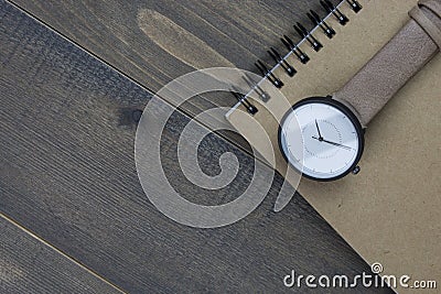 Wristwatch and notebook on wooden table Stock Photo