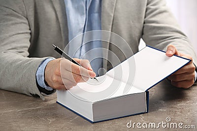 Writer signing autograph in book at tabl Stock Photo