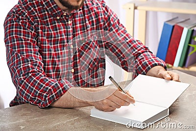 Writer signing autograph in book at table Stock Photo