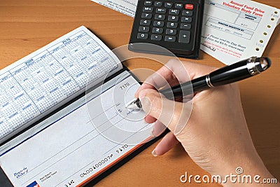 Writing a check to pay the bills, hand holding pen Stock Photo