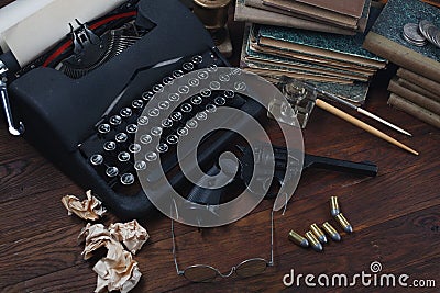 Writing a crime fiction story - old retro vintage typewriter and revolver gun with ammunitions, books, papers, old ink pen Stock Photo