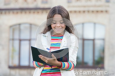 Writing a diary. School pupil do writing task outdoors. Happy child write in copybook. Making notes. Writing lesson Stock Photo