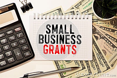 Writing note shows the text Small Business Grants Stock Photo