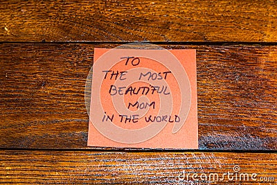 Writing to the most beautiful mom in the world on memo post reminder. Text on sticky paper. Mother`s day concept Stock Photo