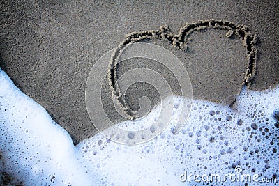 written on the sand are about to be erased by the waves. Stock Photo