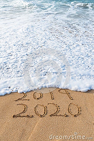2019 2020 written in the sand with a wave erasing 2019 Stock Photo