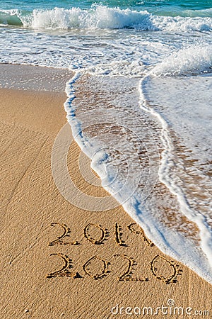2019 2020 written in the sand with a wave erasing 2019 Stock Photo