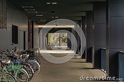 Small path under modern buildings of new estate with dark facades and bike parking stands Editorial Stock Photo