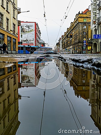 Cityscape of Pilsudskiego street with riding tram reflected in puddle Editorial Stock Photo