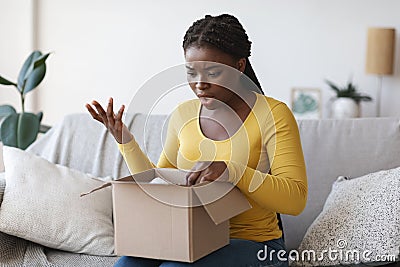 Wrong Parcel. Shocked frustrated black woman unpacking box, suffering from shipping mistake Stock Photo