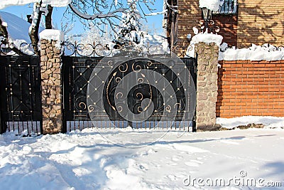 Wrought iron gates with bronze elements. Red brick fence Stock Photo