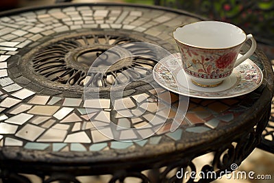 wrought iron table with mosaic tiles, empty teacup, and saucer Stock Photo