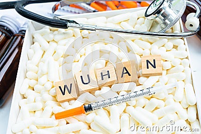 Wuhan keyword on wood block on medical pill with syringe Stock Photo