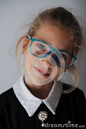 Wunderkind little caucasian girl in blue eyeglasses and school black and white uniform smiling portrait Stock Photo